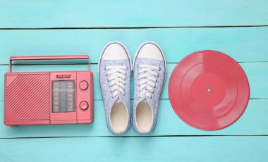 Yaratıcı retro tasarımı. Retro Sneakers ve vinil kayıt, mavi ahşap arka planda radyo alıcısı. Minimalizm. Üst Manzara. Düz yatıyordu