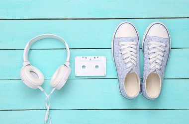 Yaratıcı düzen. Mavi ahşap arka planda spor ayakkabılar, kulaklıklar ve ses kaseti. Minimalizm. Üst Manzara. Düz yatıyordu