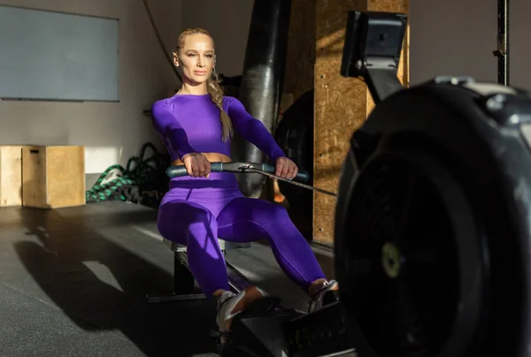 Woman doing cardio workout on rowing machine in the gym. Sportive girl works out in fitness club. Healthy lifestyle