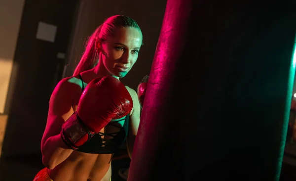 フィット女性ボクシングパンチングバッグでボクシング手袋でピンクグリーンネオンライト — ストック写真
