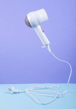 Mavi-mor arka planda saç kurutma makinesi. Minimalist güzellik ve moda hala hayat. Yaratıcı yerleşim