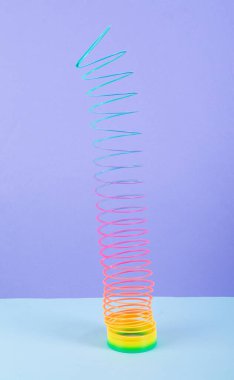 Renkli arka planda gökkuşağı plastik renkli spiral slinky oyuncak. Minimalizm
