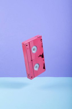 Renkli arka planda pembe video kaseti. Minimalist natürmort. Yaratıcı düzen. Sanat kavramı