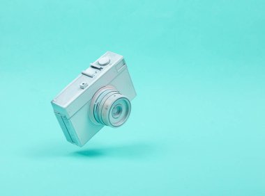 Mavi arka planda beyaz kamera var. Üç boyutlu fotoğraf. Minimalist natürmort. Yaratıcı düzen. Sanat kavramı