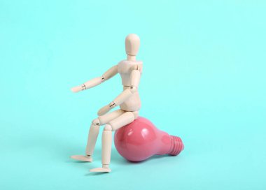 Mavi arka planda pembe ampullü tahta kukla.