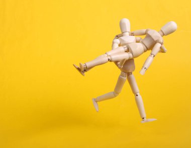 Tahta kukla sarı arka planda kuklayla kol kola koşuyor.