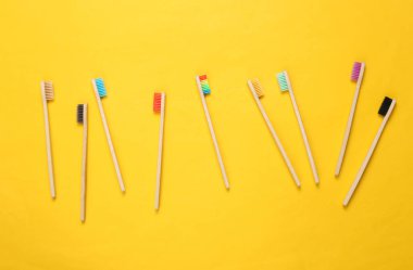 Sarı arka planda bir sürü çevre dostu bambu diş fırçası. Üst görünüm.