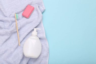 Hijyen, güzellik, bakım konsepti. Sabun, diş fırçası ve mavi arka planda havlusu olan bir şişe krema.