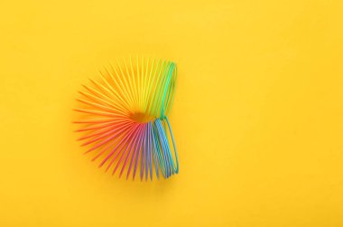 Sarı arka planda gökkuşağı plastik çok renkli spiral slinky oyuncak