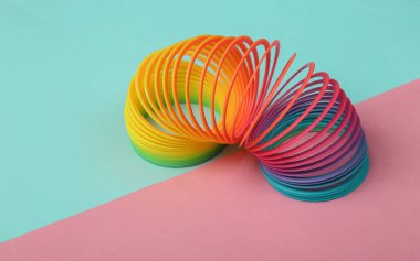 Pembe arka planda gökkuşağı plastik çok renkli spiral slinky oyuncak