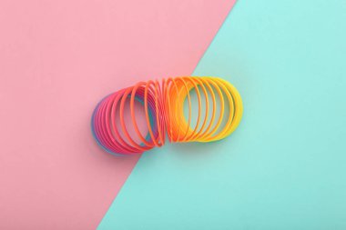 Pembe arka planda gökkuşağı plastik çok renkli spiral slinky oyuncak