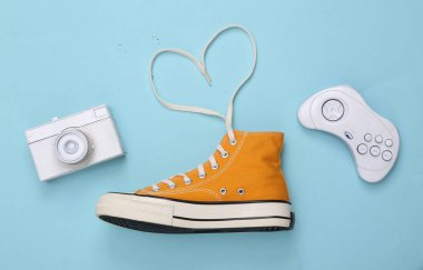 Yaratıcı retro 80 'lerin düzeni. Bağcıklı spor ayakkabılar, mavi arka planda kalp, kamera ve oyun alanı şeklinde katlanmış. Üst görünüm