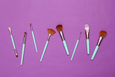 Makeup brushes on purple background. Beauty layout.