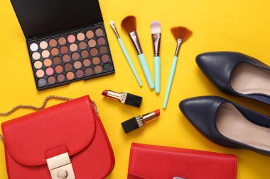 Kadın aksesuarlarının düz kompozisyonu, sarı arka planda kozmetik ürünleri. Üst görünüm