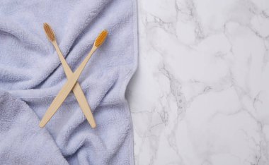 Eco-friendly bamboo toothbrushes with towel on marble surface