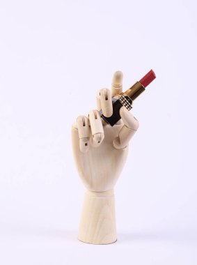 Tahta el, beyaz arka planda ruj tutuyor.