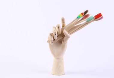 Tahta el beyaz arka planda bir sürü eko bambu diş fırçası tutuyor.