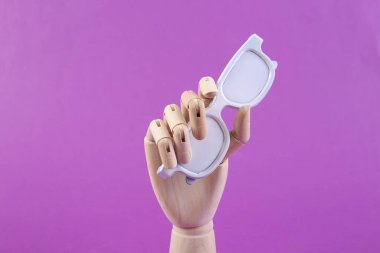 Ahşap el mor arka planda beyaz bardaklar tutuyor.