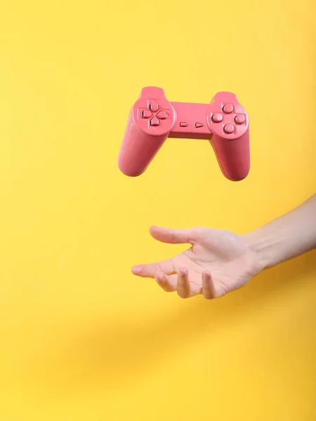 Hand Und Schwebendes Rosa Gamepad Auf Gelbem Hintergrund Minimalistisches Stillleben — Stockfoto