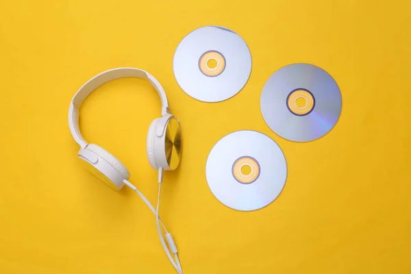 Musical layout. Headphones and cd on yellow background. Top view. Flat lay