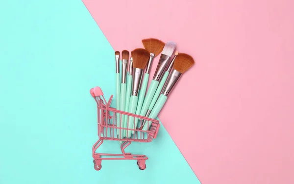 Mini Einkaufswagen Mit Schminkpinseln Auf Rosa Blauem Hintergrund Beauty Layout — Stockfoto