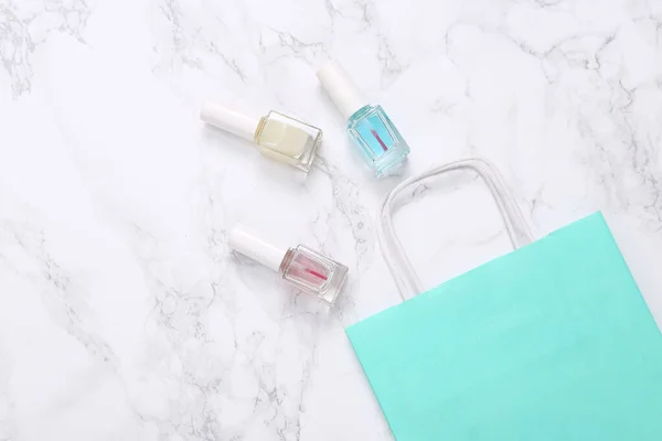 Shopping bag with Bottles of Nail Polish on Marble Surface