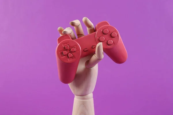 紫色の背景に木製の手を保持ゲームパッド — ストック写真