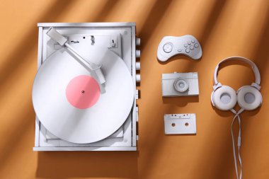 Beyaz vinil plak çalar ve turuncu arka planda modaya uygun çizgili gölgeli retro aksesuarlar. Minimalizm müzik konsepti. Yaratıcı yerleşim
