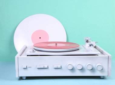 Mavi arka planda beyaz vinil plak çalar. DJ ekipmanları. Minimalizm müzik konsepti. Yaratıcı yerleşim