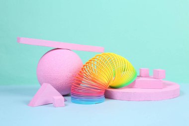 Gökkuşağı plastik, çok renkli, mavi arka planda geometrik şekilleri olan spiral bir oyuncak. Minimalizm. Yaratıcı natürmort