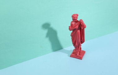 Mavi arka planda modaya uygun gölgeleri olan antik tanrıça heykeli. Yaratıcı düzen. Minimalist natürmort