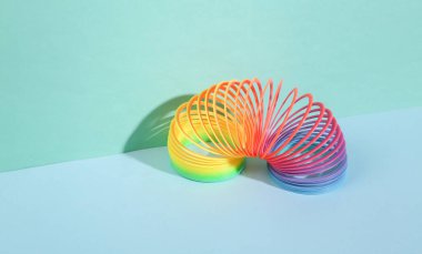 Gökkuşağı plastik renkli, mavi arka planda geometrik şekilleri olan spiral bir oyuncak. Minimalizm. Yaratıcı natürmort