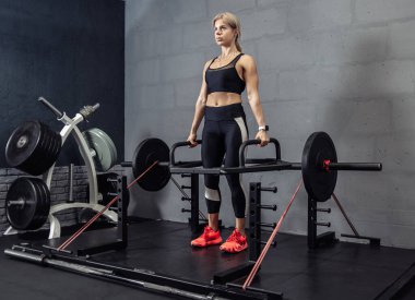 Spor salonunda ağırlıklarla egzersiz yapan bir kadın. Fit kadın halterle kaldırma egzersizi yapıyor.