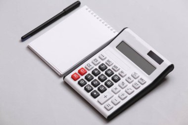 Gri arkaplanda hesap makinesi ve defter var. Üst Manzara. Düz yatıyordu