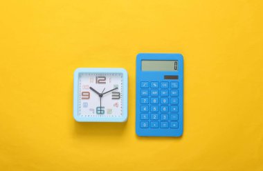 Sarı arka planda hesap makinesi ve alarm saati. Üst görünüm