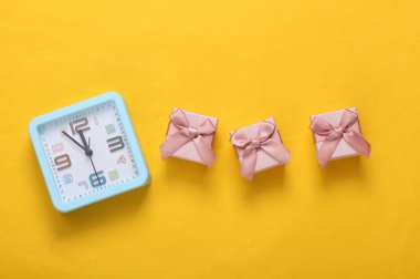 Sarı arka planda hediye kutuları ve çalar saat. Üst görünüm