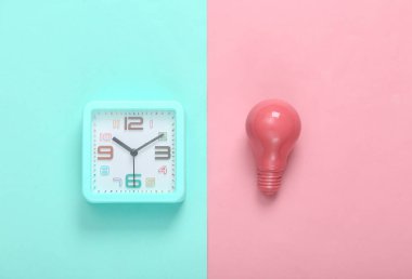 Pembe arka planda çalar saat ve pembe ampul. Minimalizm. Üst görünüm