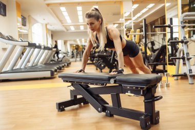 Genç fit kadın spor salonundaki bankta şınav çekiyor. Sağlıklı yaşam tarzı