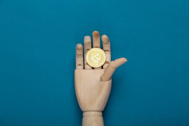 Ahşap el mavi arka planda bitcoin tutuyor