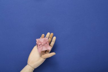 Ahşap el, mavi arka planda hediye kutusu.