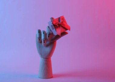 Ahşap el, pembe mavi neon ışıklı hediye kutusunu tutuyor.