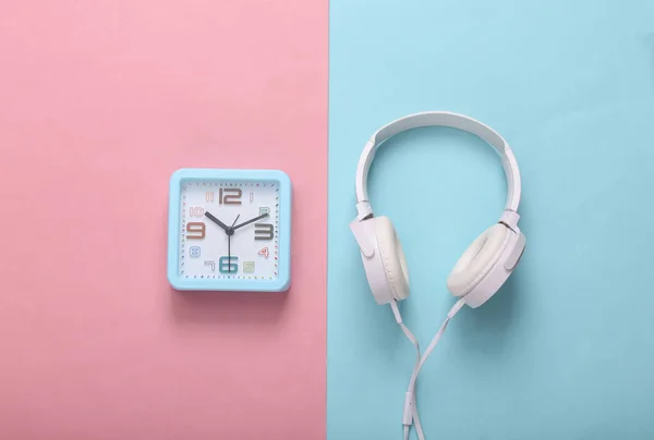 正方形闹钟 耳机为粉色蓝色背景 音乐时间 顶部视图 — 图库照片