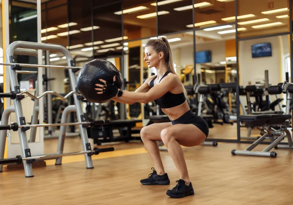 Slim fit Woman squats with medicine ball in the gym. Functional training