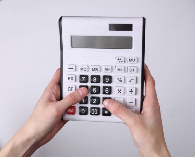 Gri arkaplanda hesap makinesi kullanan eller