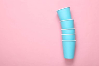 Pembe arka planda boş mavi karton bardaklar.