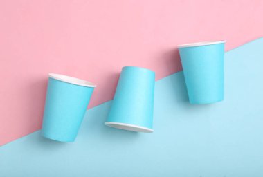 Pembe arka planda boş mavi karton kahve fincanları. Minimalizm