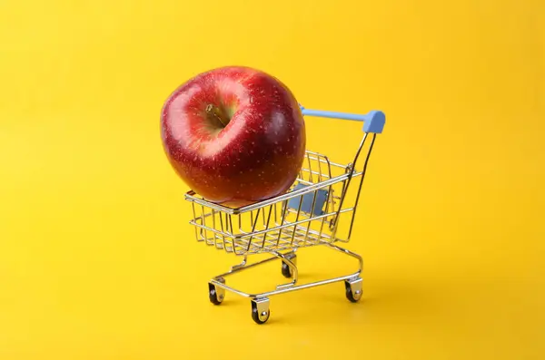 Supermarket Vozík Červeným Jablkem Žlutém Pozadí — Stock fotografie