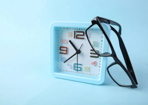 青い背景にメガネ付き目覚まし時計 — ストック写真