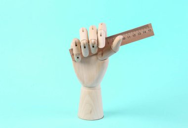 Ahşap el mavi arka planda cetvel tutuyor