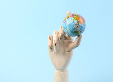 Tahta el mavi arka planda dünyayı tutuyor. Eko konsepti. Gezegeni Kaydet.